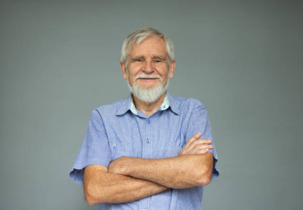 istock Senior Man Looking At Camera With Arms Crossed On Grey Background 1270233234