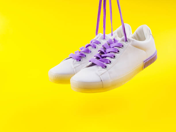 istock White sneakers with purple laces on yellow background 1270244525