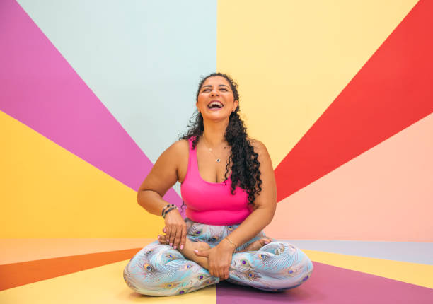 young woman in a yoga pose in a colorful room stock photo