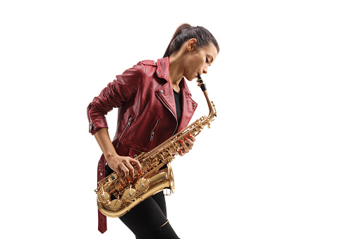 Young female musician in a leather jacket playing a saxophone isolated on white background