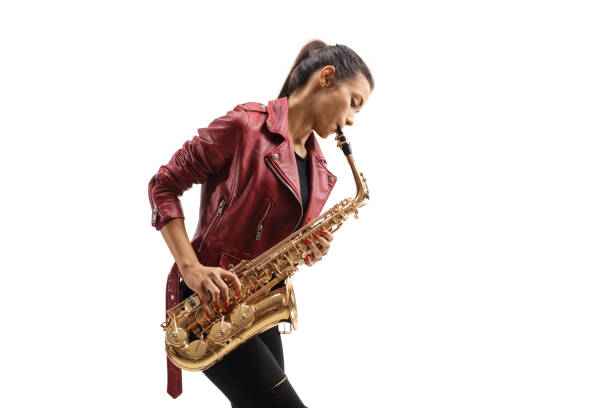 Young female musician in a leather jacket playing a saxophone Young female musician in a leather jacket playing a saxophone isolated on white background saxophone stock pictures, royalty-free photos & images