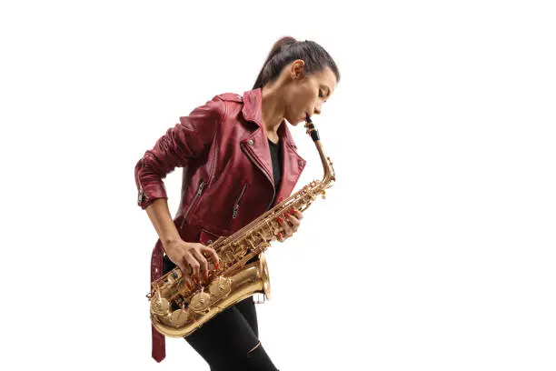 Young female musician in a leather jacket playing a saxophone isolated on white background