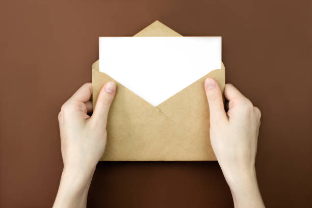 istock Envelope and white empty letter mock-up in female hands top view with copy space. Communication, information, post, mail concept. Web, social media banner template. Stock photo. 1270246524