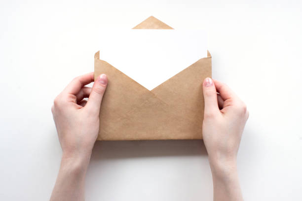 istock Envelope and white empty letter mock-up in female hands top view with copy space. Communication, information, post, mail concept. Web, social media banner template. Stock photo. 1270246559