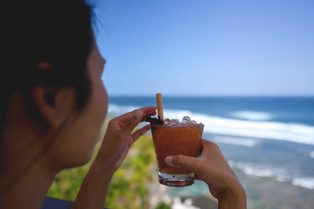 Young woman drinking a cocktail and looking at the ocean, Nikon Z7