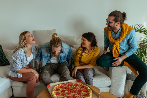 Group of friends enjoying pizza together in the living room
