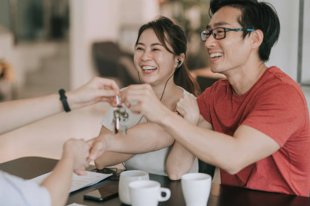 agente immobiliare cinese asiatico stringono la mano e consegnano le chiavi di casa ai suoi clienti in cucina sulle politiche - tasto pgsù foto e immagini stock