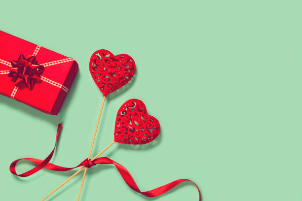 istock Abstract composition with two decorative hearts and red present box on colorful background. Valentine day theme. 1270251634