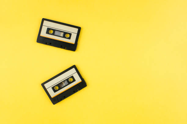 Retro audio cassette tape flat lay on colorful yellow background top view with copy space. Creative fashion design in minimal 80-s style. Music, radio, dj concept. Web banner template. Stock photo. cinta de casete de audio retro plana yacía en la vista superior de fondo amarillo colorido con espacio de copia. diseño de moda creativo en un estilo minimalista de los años 80. música, radio, concepto dj. plantilla de banner web. foto de stock.