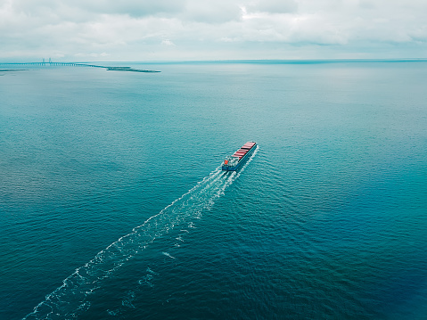 Large transport cargo ship sailing on the turquoise sea, view from the top