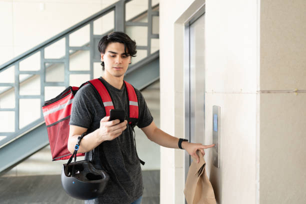 istock Delivery Man With Parcel Waiting For Elevator In Apartment 1270256738