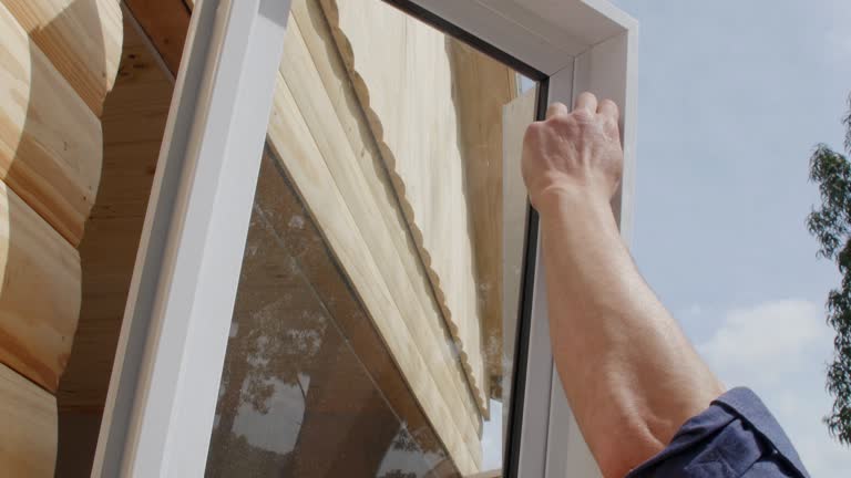 Two construction workers installing window on a new house