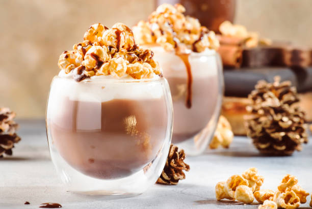 postre frío de chocolate de invierno con crema batida, palomitas de maíz y cobertura de caramelo en vasos sobre fondo beige, lugar para texto - latté cafe macchiato cappuccino cocoa fotograf�ías e imágenes de stock