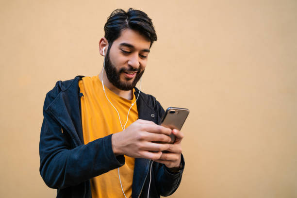 istock Latin man using his mobile phone with earphones. 1270258560