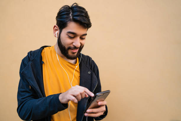 istock Latin man using his mobile phone with earphones. 1270258567