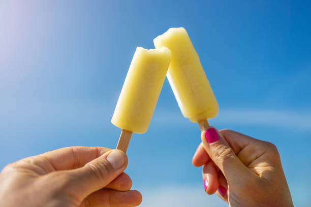Hands Holding Popsicles Against Blue Sky Hands Holding Popsicles Against Blue Sky flavored ice stock pictures, royalty-free photos & images
