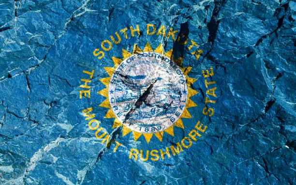 The national flag of the United States of South Dakota, stamped on a white or azure navy blue background, framed in gold with a stylized jagged sun. Rock graffiti of climbers during the ascent.