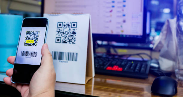istock Selective focus to customer hand holding smart phone to scan Qr code payment and barcode with blurry online shopping website on computer screen. 1270262058