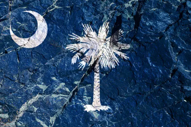 National flag of state of South Carolina USA on blue with a white palm outline in the center. A white crescent moon unfolded in sickle in upper left corner. Rock graffiti of climbers during the ascent
