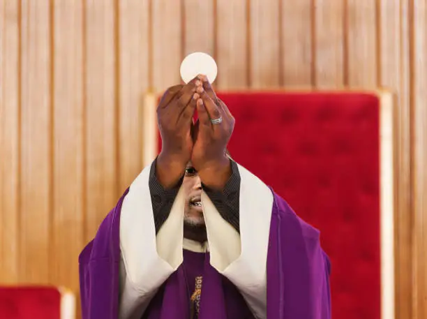 African Christian priest in the altar giving a communion wafer