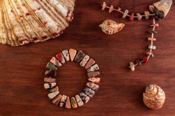 flat Lay with seashells and natural stone bracelet on a brown wooden background