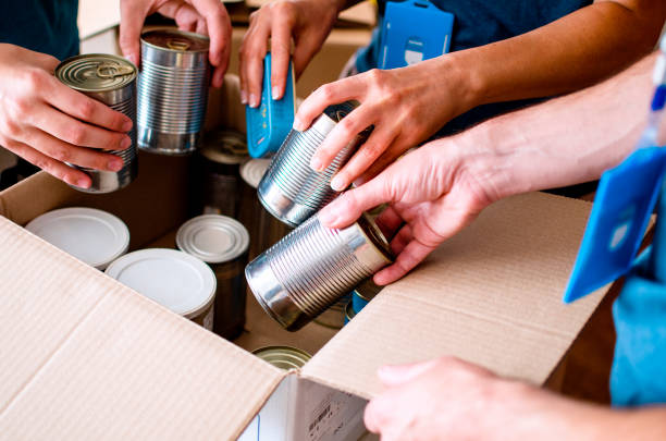 The best way to help others Volunteers Packing humanitarian aid in donation box. Group of unrecognizable people working in charitable foundation helping in crises and homeless.Donation and charity concept canned food stock pictures, royalty-free photos & images