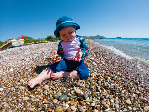 Baby at the beach playing with pebbles