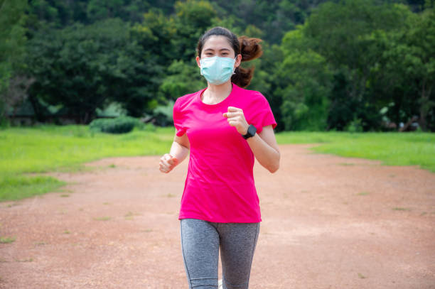 femme de coureur portant le masque tout en courant en plein air dans l’éclosion pandémique de covide-19. - medical cross photos et images de collection