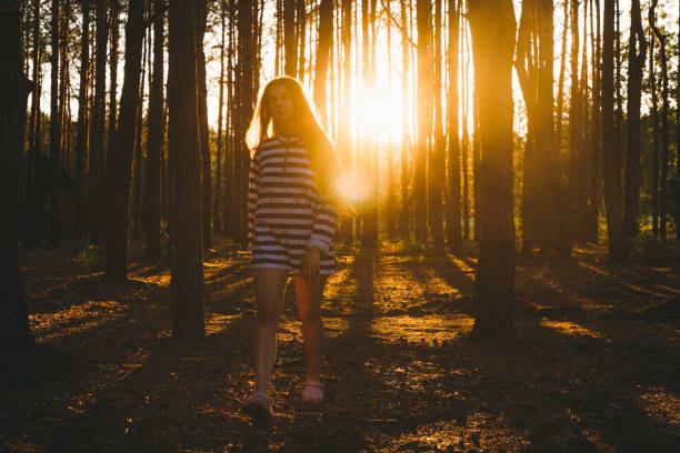 istock Young woman running at the beautiful forest during bright sunset 1270266290