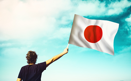 The man is waving the Japanese Flag. Patriotism concept. Horizontal composition with copy space.