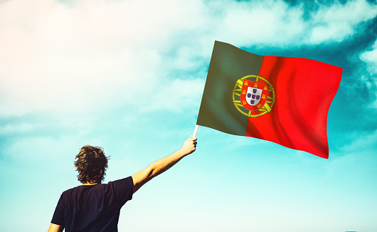 The man is waving the Portuguese Flag. Patriotism concept. Horizontal composition with copy space.