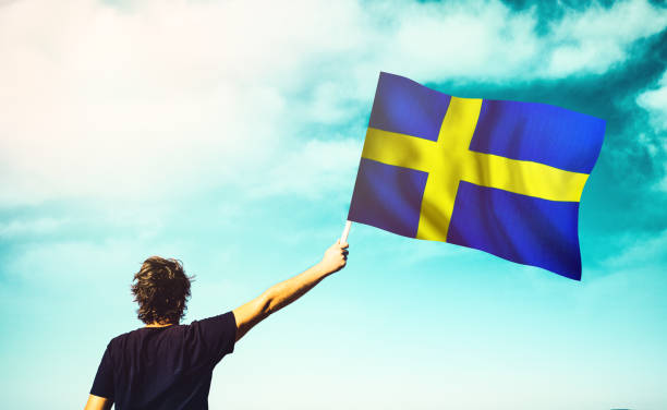 flag of Sweden fluttering in the blue sky with cumulus clouds
