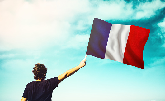 The man is waving the French Flag. Patriotism concept. Horizontal composition with copy space.