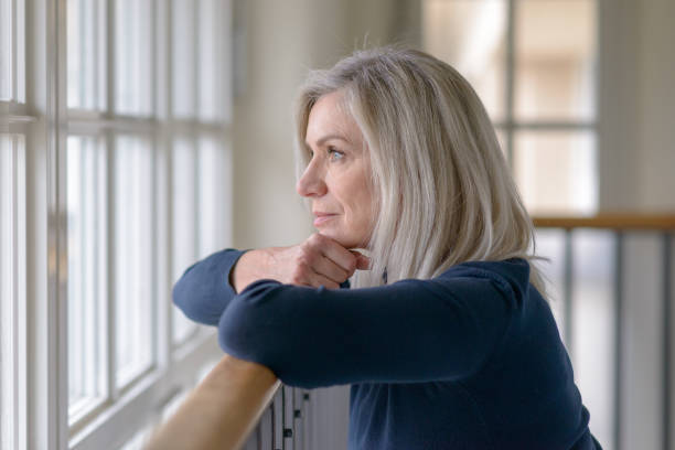 istock Sad blond woman watching through a window 1270271914