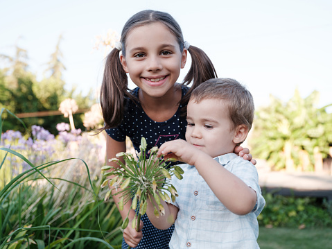 Portrait Of A Child Girl And Boy Smelling The Flowers Outdoors In A natural Park In September