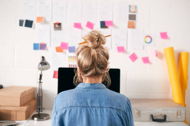 visão traseira de empresária com cabelo preso com lápis trabalhando em computador - hair bun - fotografias e filmes do acervo