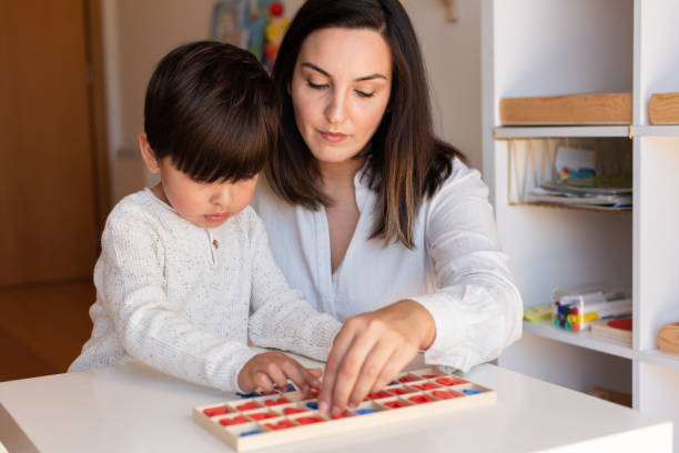 istock Kid learning to write and read with a alphabet and mother or teacher help. Homeshooling. Learning Community. Montessori School 1270275497