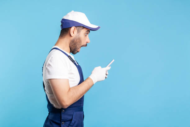 istock Side view, surprised workman in overalls reading message on mobile phone, shocked by online purchase order app 1270275536