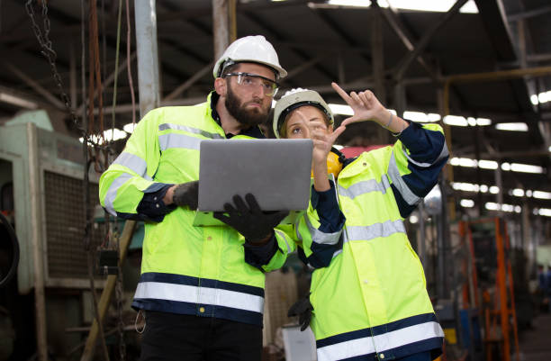 istock Two Industrial Engineers Talk with Factory Worker while Using Laptop. They Work at the Heavy Industry Manufacturing Facility. 1270276261