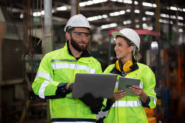 istock Two Industrial Engineers Talk with Factory Worker while Using Laptop. They Work at the Heavy Industry Manufacturing Facility. 1270276309