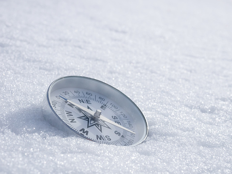 Round modern compass on the white snow, space for text. Concept for travelling and active lifestyle