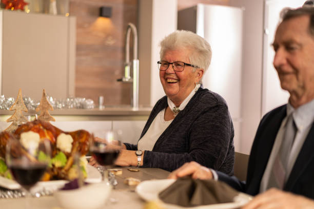 istock laughing senior woman enjoying christmas dinner 1270282606