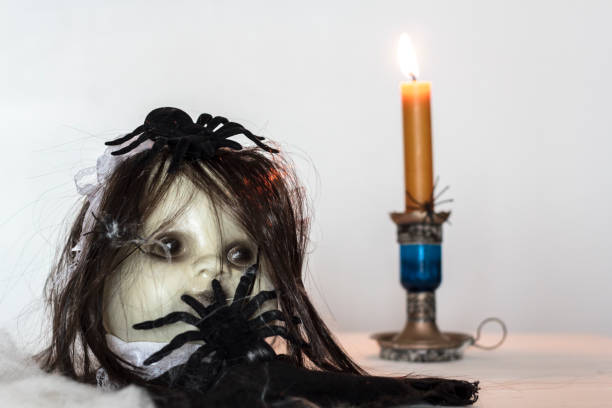 Spooky doll with spiders and lit candle. Halloween theme