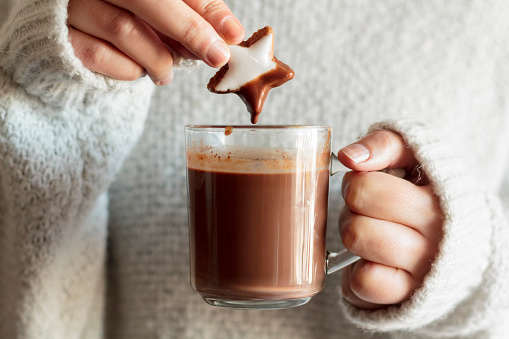 Girl hands dipping cookie in hot chocolate