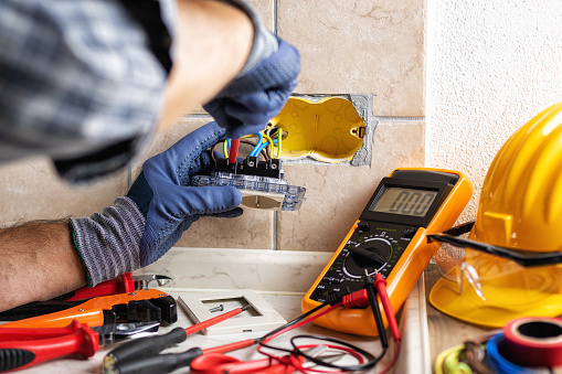 Electrician at work with screwdriver fixes the cable in the sockets of a residential electrical system. Construction industry.