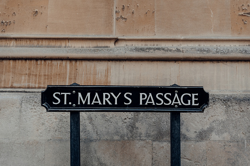 Metal street name sign on St. Marys Passage in Oxford, UK, against the building.