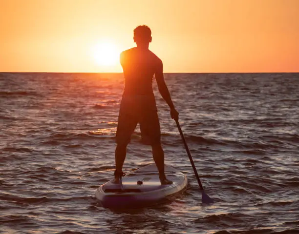 Photo of Man on SUP at sunset background