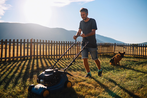 Gardener working with a lawn mower during a work hard day