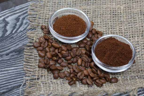 istock Coffee beans on coarse linen. Ground coffee in containers. On a surface of brushed pine boards painted black and white. 1270293810