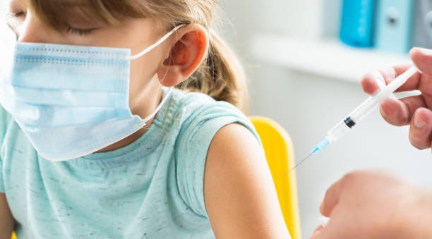医者のオフィスの小さな女の子が予防接種を受けています。covid-19コロナウイルス、インフルエンザ、危険な感染症に対するワクチンを含む注射器。ヒト、小児の臨床試験後の注射。医学の� - little girls vaccination child caucasian ストックフォトと画像